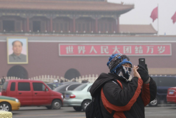 Un visiteur prend une photo sur la place Tian'anmen plongée dans un smog lourd à Beijing, le 20 février  2014. [Photo/Xinhua]