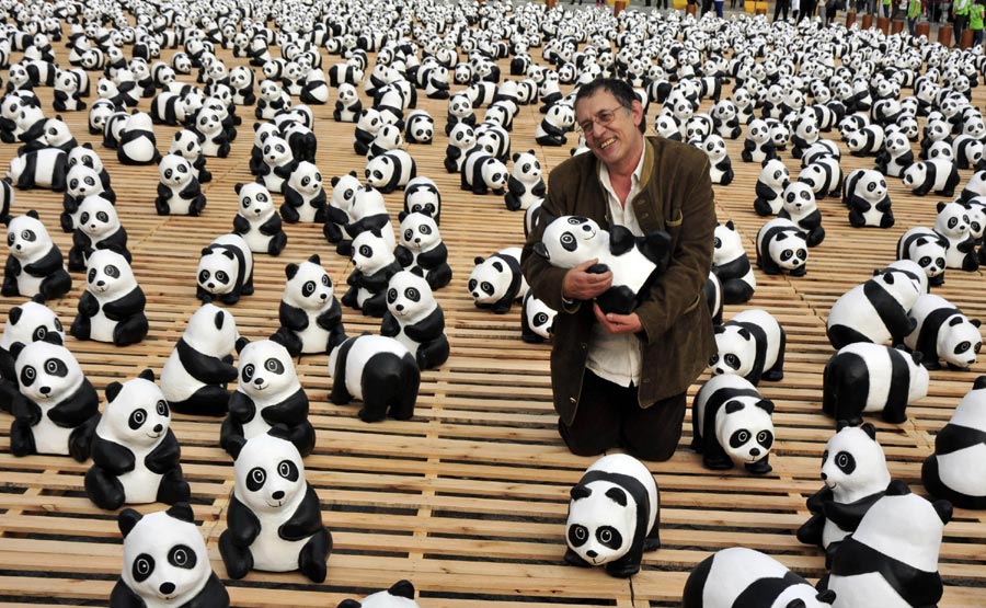 L'artiste français Paul Grangenon pose pour se faire photographier avec ses œuvres, des pandas en papier, lors de l'exposition en plein air intitulée « Pandas World Tour - Taipei » sur la Place des Citoyens à Taipei, au sud-est de Taiwan, en Chine, le 27 février 2014. Un total de 1 600 pandas et ours à collier de Taiwan fabriqués en papier respectueux de l'environnement ont été exposés ici jeudi. L'événement vise à promouvoir la protection de l'environnement et la sensibilisation du public à la conservation des animaux. Tous les pandas et ours à collier en papier exposés seront proposés pour une vente de charité après la conclusion de l'événement le 30 mars. [Photo/Xinhua]