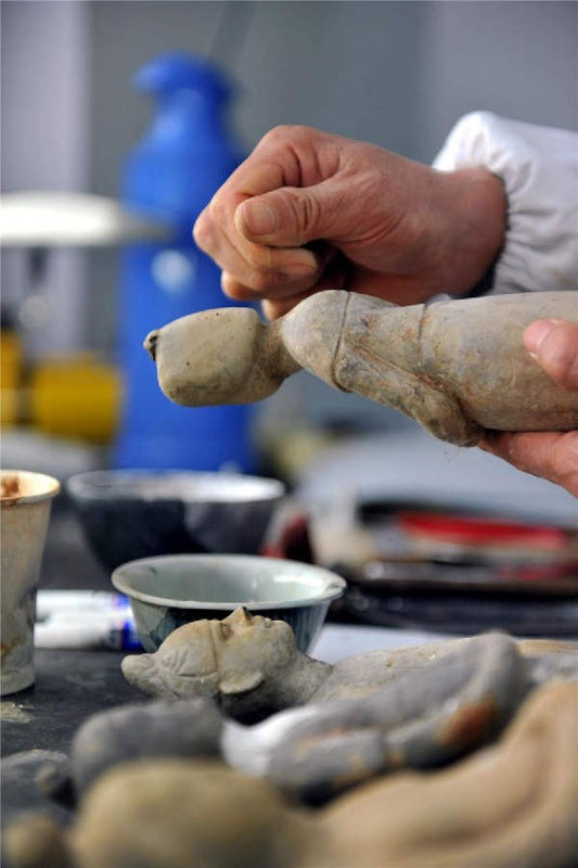 Zhou Xueshan polit les statuettes en terre cuite en cours de restauration.
