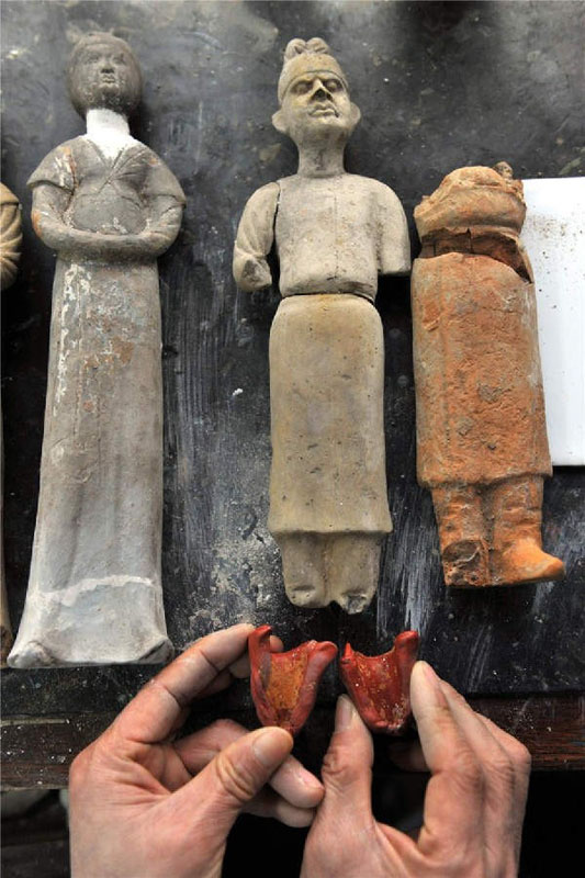 Zhou Xueshan remplit les parties manquantes des statuettes en terre cuite en utilisant un moule spécialement conçu.
