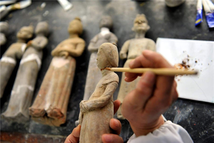 Zhou Xueshan ajoute de la couleur à des statuettes en terre cuite.
