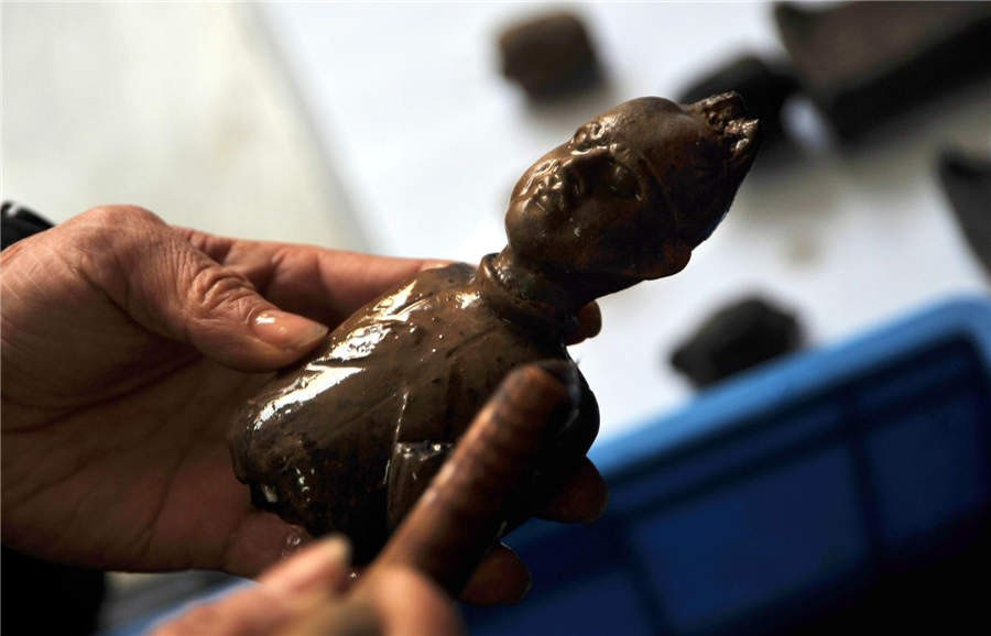 Zhou Xueshan, expert en restauration au Musée de Yangzhou, nettoie une statuette en terre cuite avant de commencer les travaux de réparation.