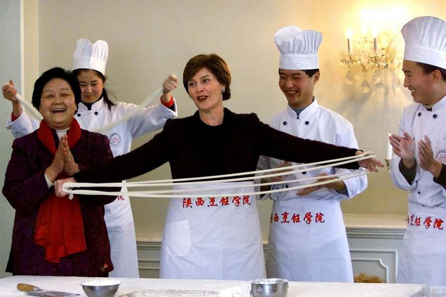 Le 21 févier 2002 à Beijing, Laura Bush apprend à faire les « nouilles tirées » auprès d'un chef chinois dans l'ambassade américaine. 