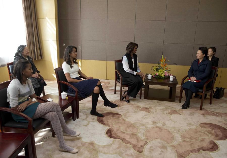 La première dame des États-Unis Michelle Obama (au centre) et ses filles Sasha (à gauche) et Malia rencontrent Peng Liyuan (à droite), l'épouse du président chinois Xi Jinping, lors de leur visite d'une classe de calligraphie traditionnelle chinoise à l'École Normale de Beijing, une école qui prépare les étudiants à l'entrée dans les universités étrangères, à Beijing le 21 mars 2014.