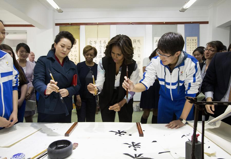 La première dame des États-Unis Michelle Obama (à gauche) est accueillie par Peng Liyuan, épouse du président chinois Xi Jinping, à son arrivée pour une visite à l'École Normale de Beijing, une école qui prépare les étudiants à l'entrée dans les universités étrangères, à Beijing le 21 mars 2014.