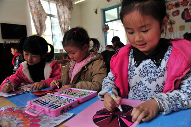 Des enfants fabriquent des masques d'opéra dans une école maternelle du Comté de Zigui, dans la Province du Hubei, le 26 mars 2014, pour célébrer la Journée mondiale du théâtre.