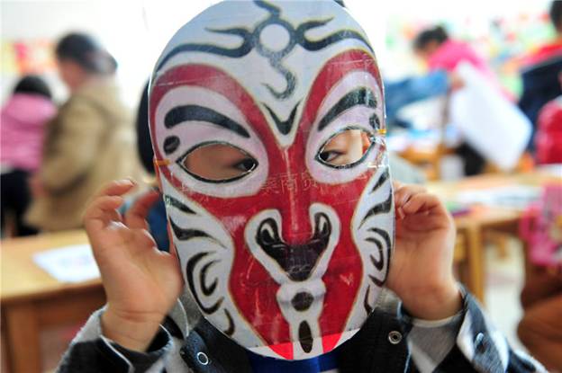 Un enfant montre son masque d'opéra fait à la main dans une école maternelle du Comté de Zigui, dans la Province du Hubei, le 26 mars 2014, pour célébrer la Journée mondiale du théâtre.