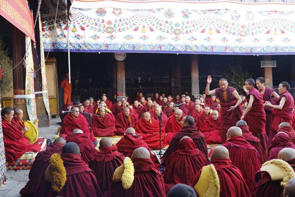 Des membres du jury d'examen débattent avec des candidats au titre de Geshé Lharampa lors de l'examen annuel de dialectique pour obtenir le plus haut degré du bouddhisme tibétain au temple Jokhang, le 3 avril. [Photo Pladen Nyima / chinadaily.com.cn]