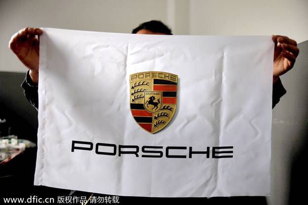 Un ouvrier d'usine montre une bannière portant l'emblème de Porsche, une marque de voitures de luxe, dans les locaux de la société Hanghzou Donghao Flag Co, dans la Province du Zhejiang, dans l'Est de la Chine, le 8 avril 2014. 