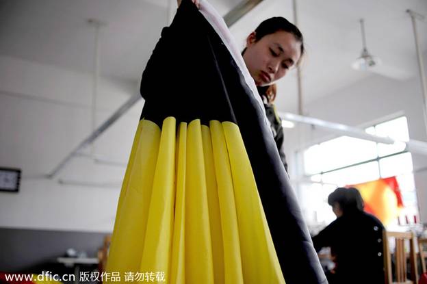 Une ouvrière inspecte les drapeaux nationaux qu'elle a produits dans les locaux de la société Hangzhou Donghao Flag Co, dans la Province du Zhejiang, en Chine de l'Est, le 8 avril 2014.