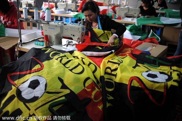 Les ouvrières travaillent 24 heures sur 24 à faire les drapeaux nationaux des équipes qualifiées pour la Coupe du Monde afin de respecter l'échéance du 14 avril, dans les locaux de la société Hangzhou Donghao Flag Co, dans la Province du Zhejiang, en Chine de l'Est. Photo prise le 8 avril 2014.