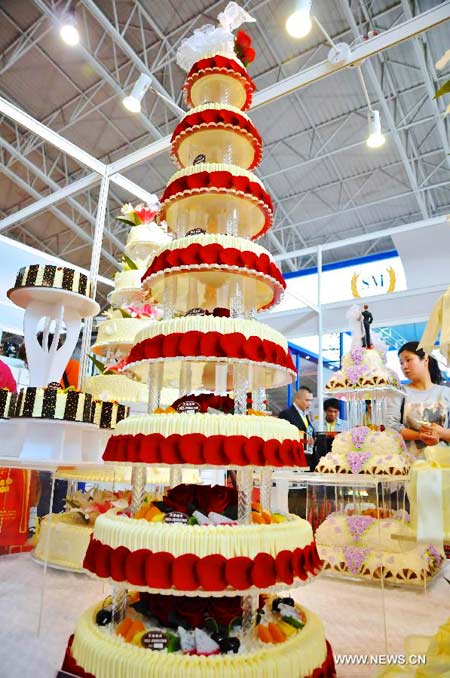 Les visiteur regardent un modèle de gâteaux en forme de tour pendant l'Exposition internationale de la boulangerie, de la glace, et de la transformation et de l'emballage alimentaires 2014 à Beijing, capitale de la Chine. L'exposition, qui a débuté le 8 avril, durera trois jours. [Photo/Xinhua]