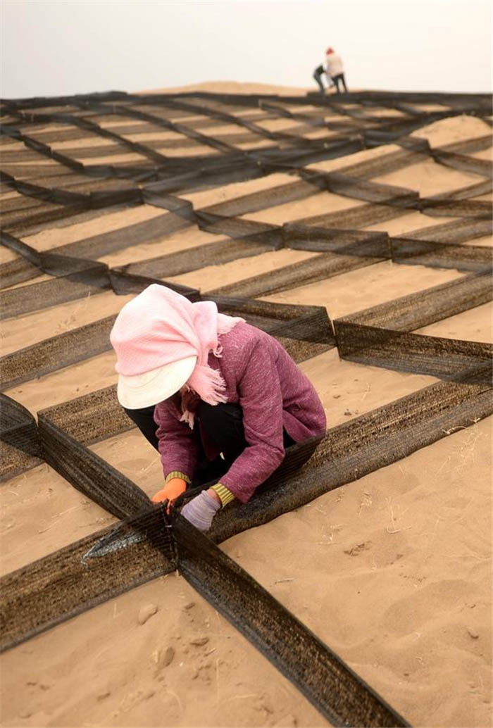 Un villageois utilise des filets de nylon pour transformer le sable en blocs. [Photo/Xinhua]