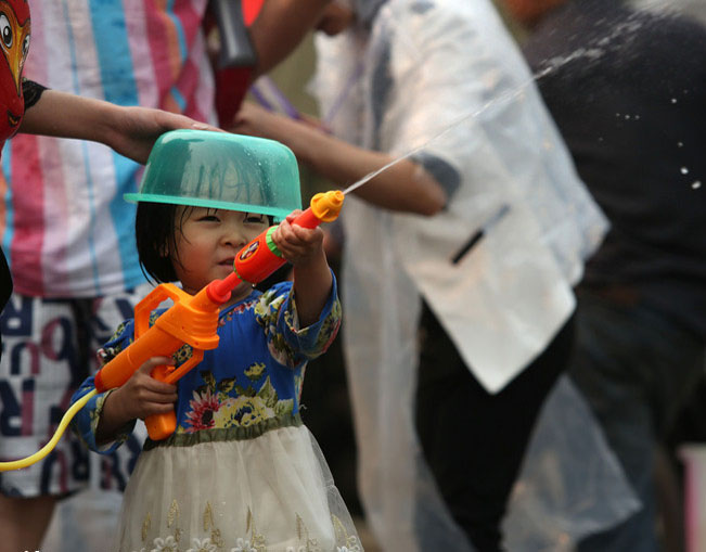 Une fillette utilise un pistolet à eau pour projeter de l'Eau, et un bol en plastique en guise de casque pour éviter les éclaboussures, pendant le Festival du Songkran, dans la ville de Jinghong, dans le Xishuangbanna, le 15 avril.