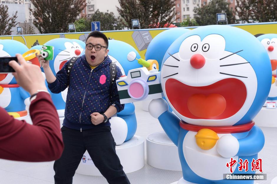 Mercredi 16 avril, devant le centre commercialJoy City du district de Chaoyang à Beijing, un visiteur prend la pose avec des statues de Doraemon en pré-exposition. (Photo : Chinanews/Yi Ting)