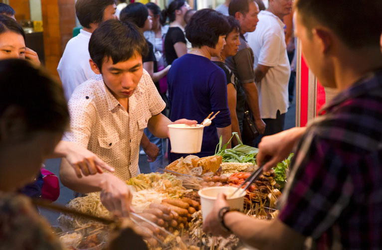 Des gens mangent des fruits de mer dans une rue de spécialités locale.