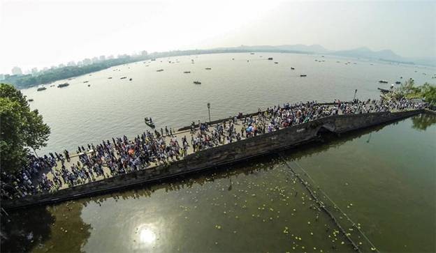 Des touristes visitent le site pittoresque du Lac de l'Ouest à Hangzhou, capitale de la Province du Zhejiang, dans l'Est de la Chine, le 1er mai 2014. Le Lac de l'Ouest a connu sa période de pointe des voyages le jour même de la Fête du Travail, le premier jour des congés de 3 jours. [Photo / Xinhua]