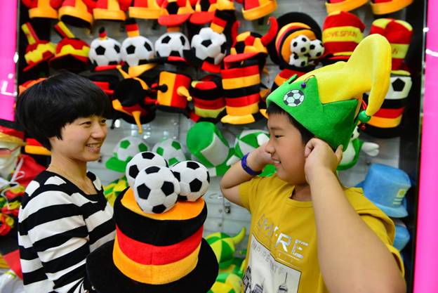 Des jeunes fans de football essaient des couvre-chefs de leurs équipes favorites, mardi à la Cité du Commerce International d'Yiwu, dans la Province du Zhejiang, dans l'Est de la Chine.