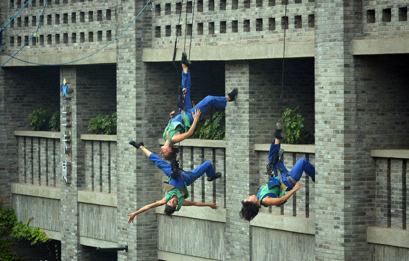 Reliés par un câble, trois danseurs professionnels ont offert au passants une performance spectaculaire sur le mur extérieur d'un bâtiment de la ville de Chongqing du sud-ouest de la Chine, le 9 mai 2014. Dans cet art, les danseurs ont créé l'illusion de voler et de défier la gravité. 