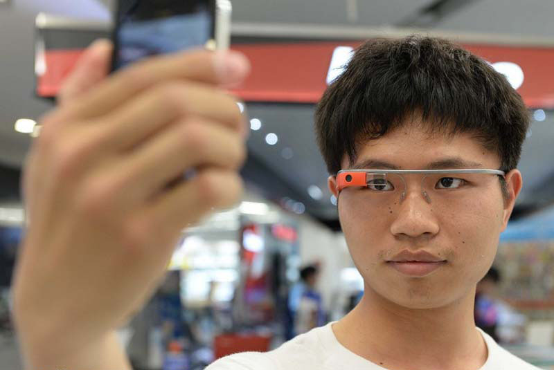 Un client utilise son smartphone pour prendre des selfies, essayant les Google Glass chez Suning, un magasin d' appareils électroménagers, à Shanghai, le 8 mai 2014. 