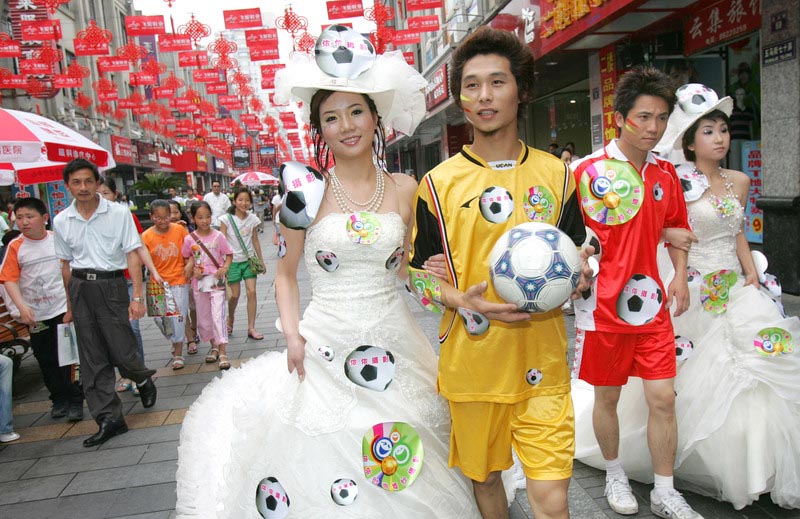 Lors d'un défilé de mode sur le thème du mariage, les mariés ont laissé tomber le costume de mariage traditionnel pour porter des maillots de football et les épouses ont décoré leur robe de mariage avec des autocollants inspirés du football à Wuma Road, dans la ville de Wenzhou (Province du Zhejiang), le 3 juin 2006. Les Chinois ont célébré la Coupe du Monde 2006, qui a débuté cette année-là le 9 juin en Allemagne, à leur manière.