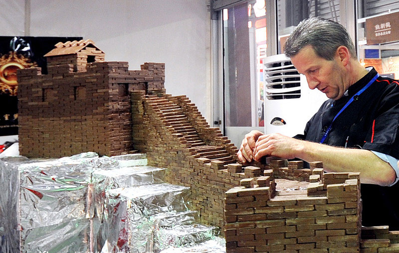 Un chocolatiers belge s'active sur un segment miniature de la célèbre Grande Muraille, composé de 100 kilogrammes de chocolat noir, lors du Salon International de l'alimentation (SIAL) à Shanghai mercredi.